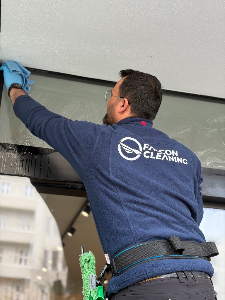 Falcon Cleaning Mitarbeiter bei der professionellen Fensterreinigung in gebrandeter Arbeitskleidung
